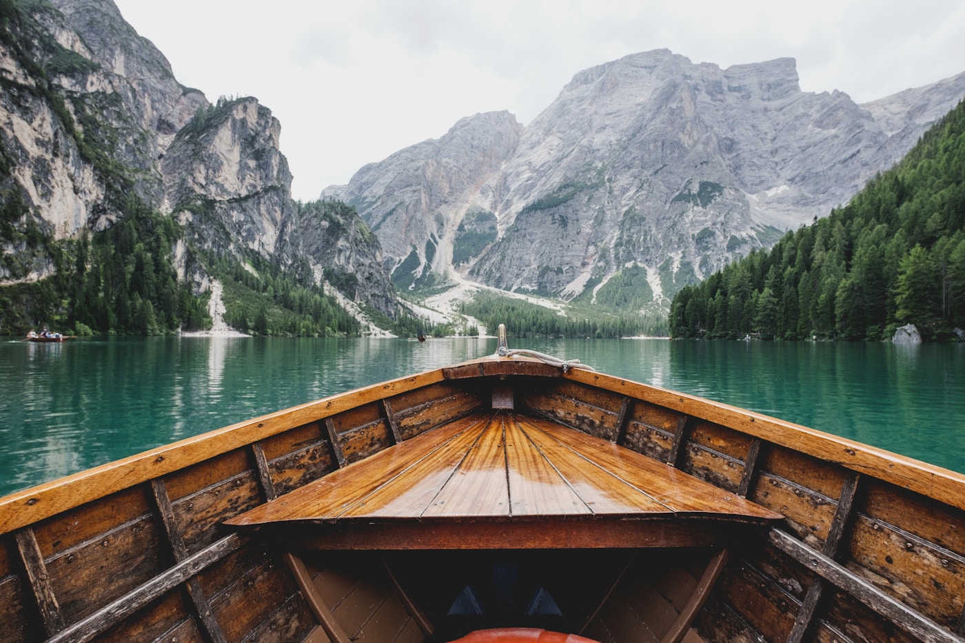 Wooden boat on a lake surrounded by forest and mountains